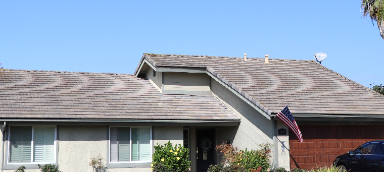 Roof of single-family home with American flag displayed on porch.