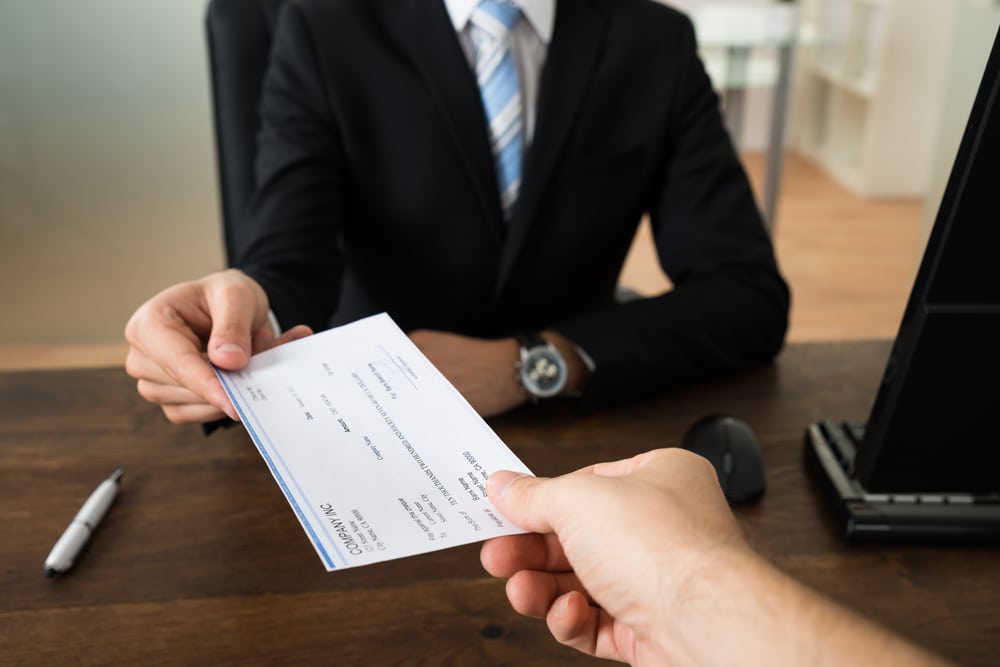 Boss handing worker a paycheck