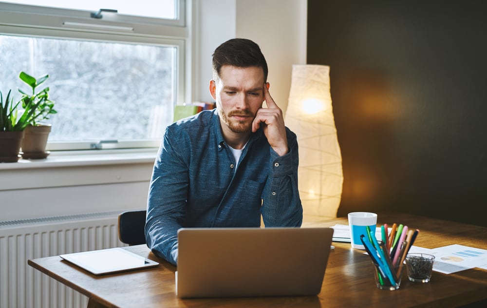 Millennial man studies reviews on computer behind desk