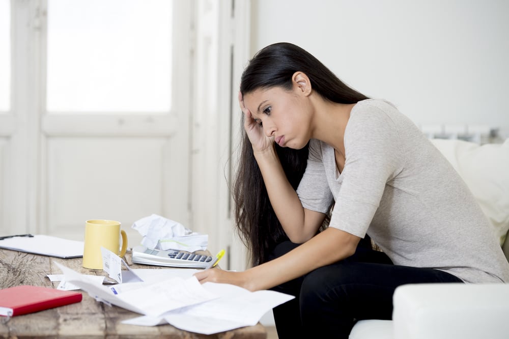 Young woman sitting at home, stressed about bills