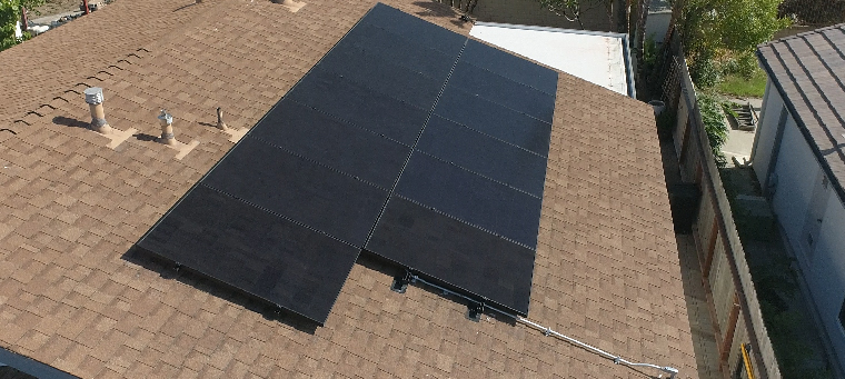 Thirteen solar panels on asphalt shingle roof of single story home.